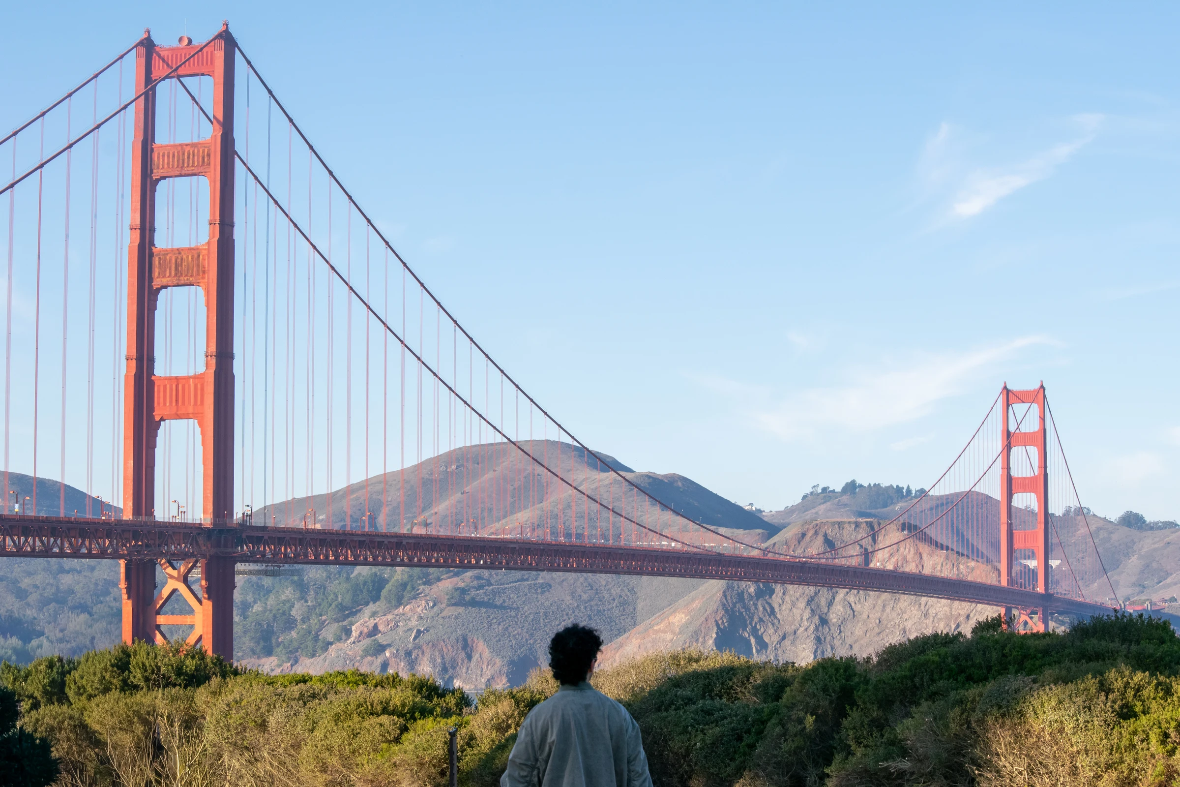 Adrian looking toward the Golden Gate Bridge, its red towers and cables stretching across the hills.