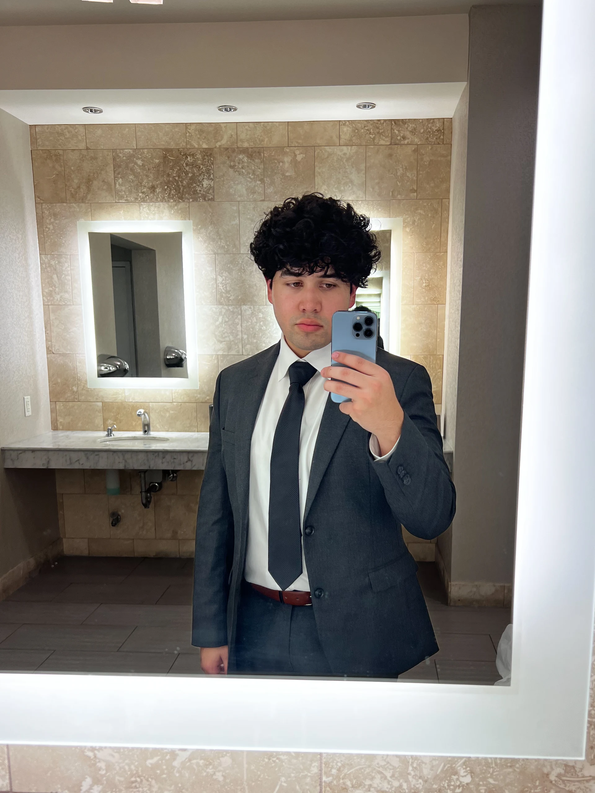 Adrian in a suit, taking a mirror photograph during his BNY internship.