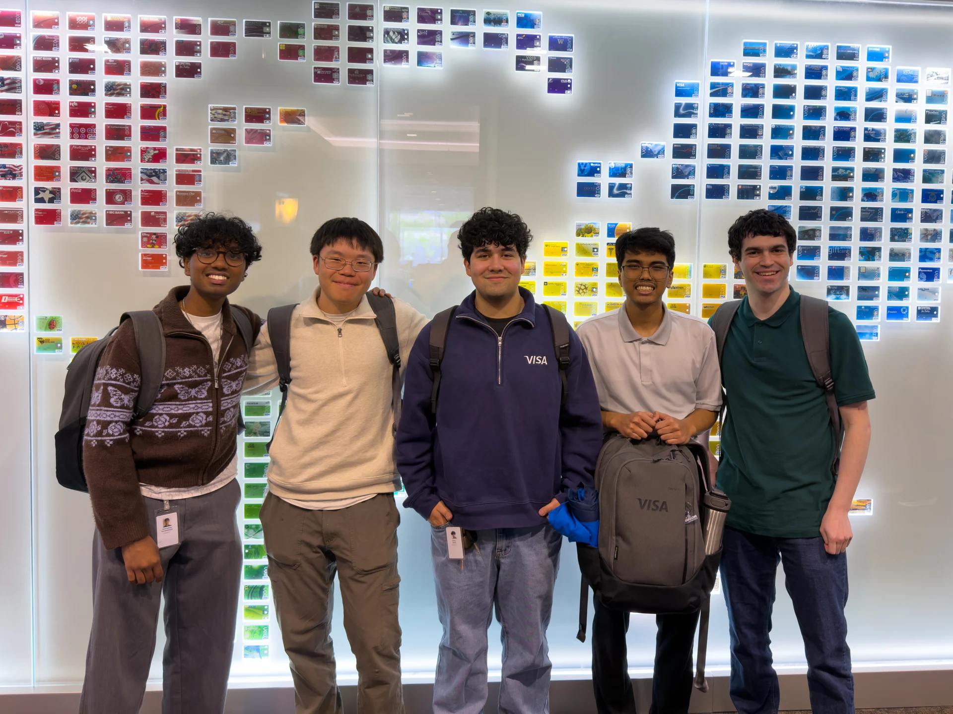 Adrian and four colleagues in front of a wall of Visa cards.